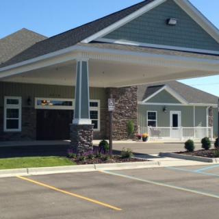 A modern building with a covered entrance and a parking lot.
