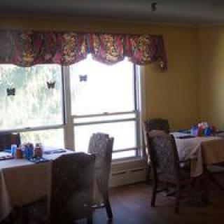 A cozy dining room with tables and chairs near a large window.