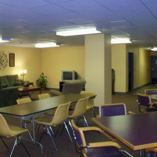 A cozy common area with tables, chairs, and a television.