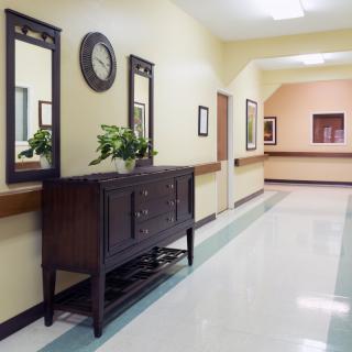 A well-decorated hallway featuring a wooden cabinet, mirrors, a clock, and a potted plant.