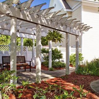 A tranquil garden pergola with wooden benches and lush greenery.