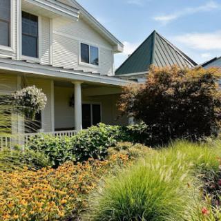 A beautiful house surrounded by a vibrant garden with colorful flowers and lush greenery.