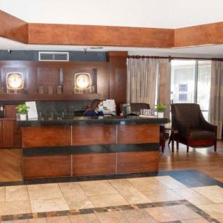 A modern hotel lobby with a wooden reception desk and comfortable seating area.