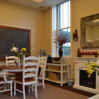 A cozy dining room with a round table, chairs, and a decorative fireplace.