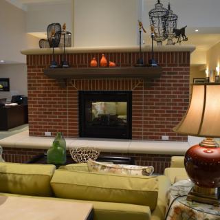 A cozy living room featuring a central brick fireplace, accented with stylish decor and comfortable seating.