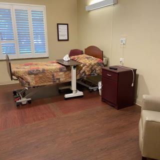 A well-equipped hospital room with a bed, side table, and chair.