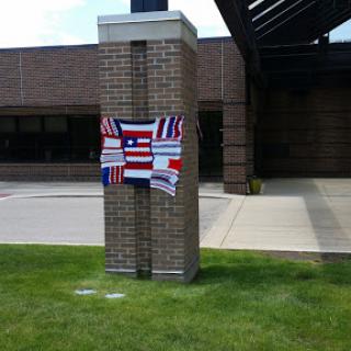 A decorative display featuring multiple flags on a pillar outside a building.
