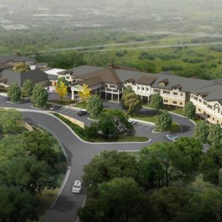 An aerial view of a complex surrounded by greenery and winding roads.