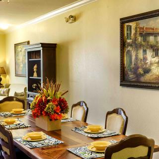 A well-decorated dining room with a wooden table, chairs, and vibrant floral centerpiece.