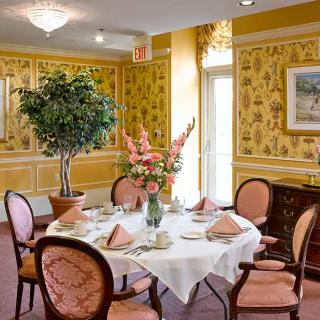 An elegantly set dining table with a floral centerpiece in a tastefully decorated room.