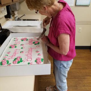 A woman is admiring a beautifully decorated cake in the kitchen.