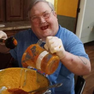 A person happily preparing food with a blender in the kitchen.