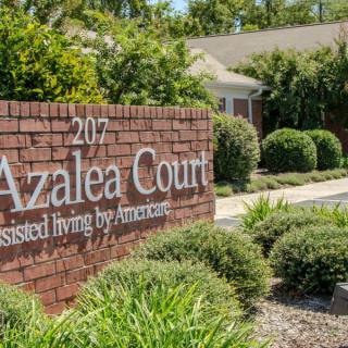 A sign for Azalea Court, an assisted living facility, surrounded by landscaping and greenery.
