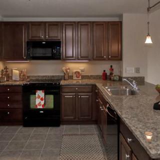 A modern kitchen with dark wood cabinets and granite countertops.