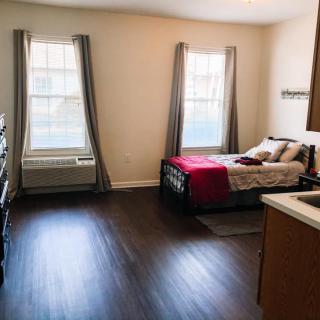 A modern and minimalist bedroom with ample natural light and wood flooring.