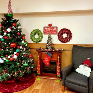 A festive Christmas corner featuring a beautifully decorated tree, colorful wreaths, and cozy seating.