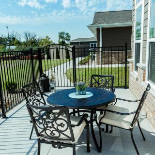 A sunny backyard patio with a round metal table and four matching chairs.