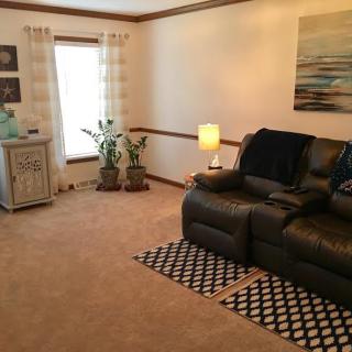 A cozy living room with a leather sofa, decorative plants, and warm lighting.