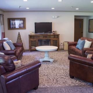 A cozy living room featuring leather sofas, a central coffee table, and a television.