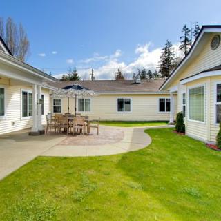 A sunny courtyard with patio furniture and well-maintained grass lawn surrounded by residential buildings.