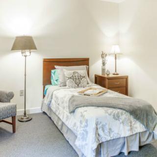 A cozy bedroom with a single bed, nightstand, and lamps.