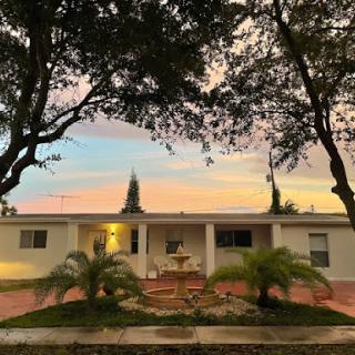 A serene evening view of a charming house surrounded by trees and a beautiful sunset.