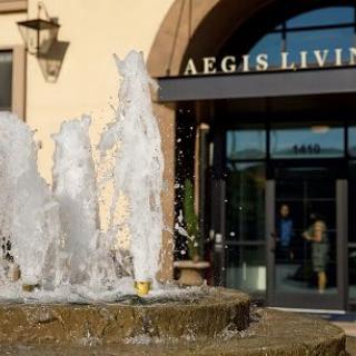 A fountain in front of the entrance to a building labeled 'Aegis Living'.