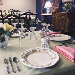 Elegantly set dining table with floral plates and neatly arranged silverware.