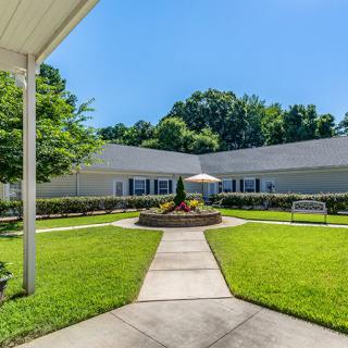 A well-maintained building with a landscaped lawn and walkway under a clear blue sky.