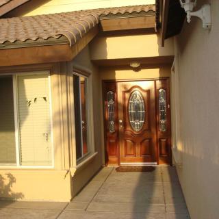 A residential house entrance with a wooden front door and adjacent windows.