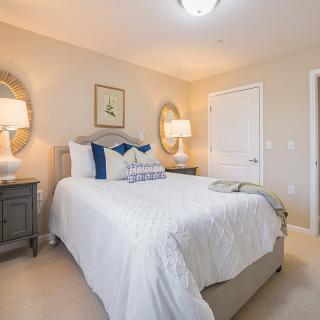 A cozy and well-decorated bedroom featuring a comfortable bed, two lamps on side tables, and decorative mirrors.