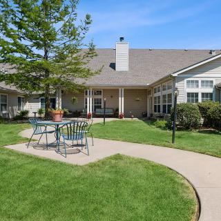 A sunny backyard with a well-maintained lawn and patio furniture.