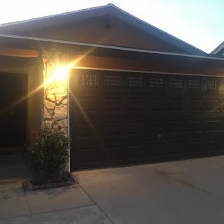 The exterior of a house with an illuminated garage at dusk.