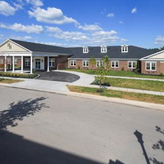 A modern, single-story brick building under a clear blue sky with scattered clouds.