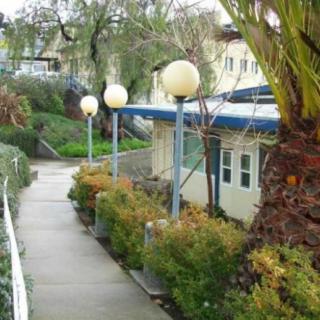 A scenic walkway lined with trees and spherical lamps, adjacent to buildings.