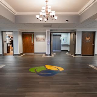 A spacious and modern lobby featuring a stylish chandelier and elegant wooden flooring.