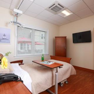 A clean and well-furnished hospital room with a bed, television, and window.