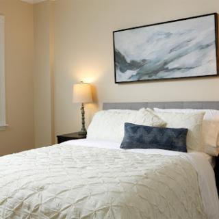 A cozy and elegantly styled bedroom featuring a comfortable bed, decorative pillows, and soft lighting.