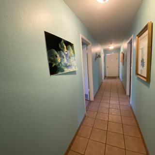 A hallway with tiled flooring, adorned with paintings and multiple doors along the walls.
