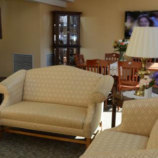 A cozy living room featuring a beige sofa set, a lamp, and a television in the background.
