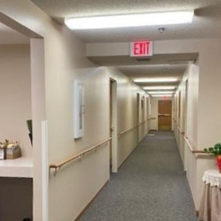 A well-lit indoor hallway with multiple doors and a visible exit sign.