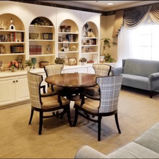 A cozy living room featuring a dining table with chairs, surrounded by bookshelves and a comfortable sofa.