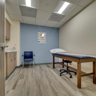 A clean and modern medical examination room, equipped with a treatment table and a chair for patients.