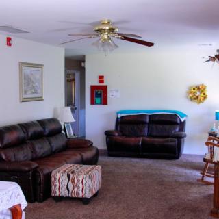 A cozy living room with sofas, a ceiling fan, and home decor.