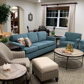 A cozy living room with blue sofas and armchairs arranged around a round coffee table.