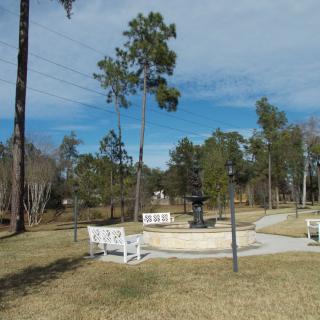 A serene park setting with a central fountain, surrounded by trees and benches.