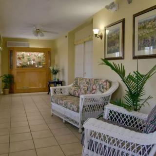 A cozy lobby area with wicker furniture, plants, and artwork on the walls.