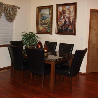 A cozy dining room with a wooden table, black chairs, and decorative artwork on the wall.