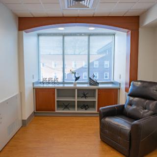 A cozy corner of a room featuring a comfortable chair and a window with natural light.
