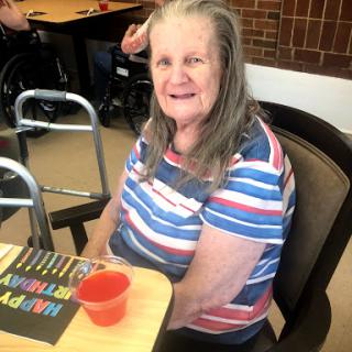 An elderly woman enjoying a cheerful moment in a social setting.